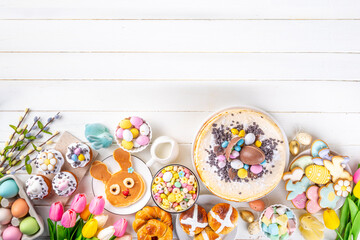 Easter brunch, breakfast food, Kids Easter party buffet. Various traditional Easter sweets, candy, pasties and baking - cross buns, cheesecake, chocolate eggs, pancakes, cupcakes, top view copy space
