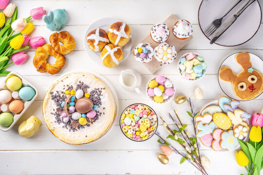 Easter brunch, breakfast food, Kids Easter party buffet. Various traditional Easter sweets, candy, pasties and baking - cross buns, cheesecake, chocolate eggs, pancakes, cupcakes, top view copy space