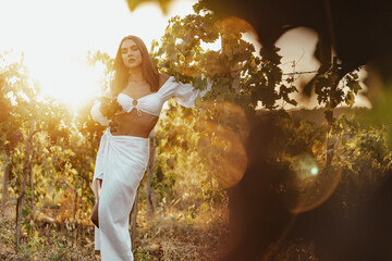 Beautiful young blonde woman walking outdoors in vineyard in summer.
