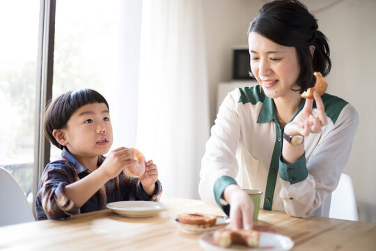 おやつのドーナツを食べる母親と男の子
