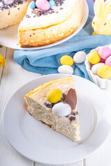 Homemade Easter cheesecake, sweet cottage cheese baking, with Easter chocolate eggs and chocolate drops, with holiday decorations and spring flowers