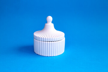 Fototapeta na wymiar White ceramic trinket box isolated on blue background 