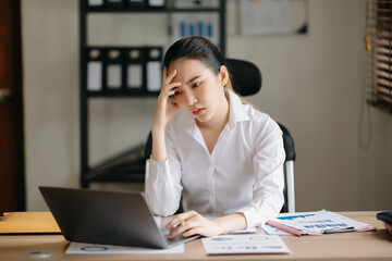 Asian business woman is stressed, bored, and overthinking from working on a tablet at the  office...