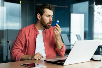 Asthma and respiratory problems in office worker, mature man coughing and using medicine in inhaler...