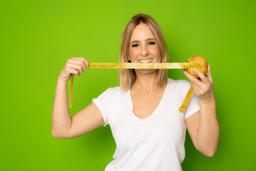 Close up portrait of an excited young woman with open mouth looking at a measuring tape isolated...