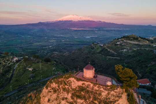 Aerial view of a small church on Monte Calvario in Centuripe at sunset with Etna Volcano in background, Enna, Sicily, Italy.