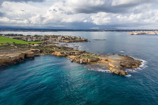Aerial view of Punta della Mola with Ortigia Island in background in Plemmirio Natural Reserve in Syracuse, Sicily, Italy.