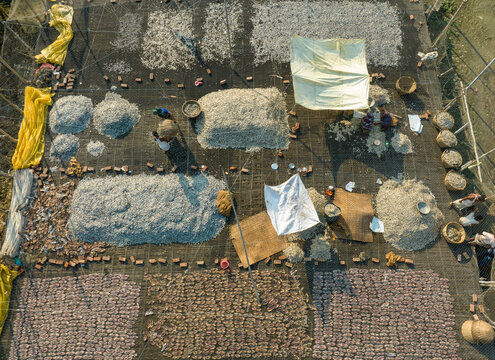 Aerial view of people working in a fish market drying fish at Lalpur Launch Ghat along Meghna River, Chattogram, Bangladesh.