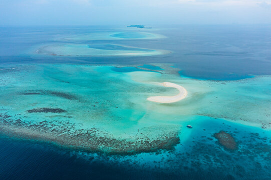 Aerial view of a desert island among the Atolls surrounded by the Indian Ocean, Maldives archipelagos.