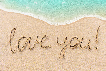 Love You! written text on sandy beach with beautiful blue ocean wave on background