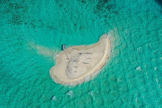 Aerial view of people with a boat on a small island with white sand, Thinadhoo, Vaavu Atoll, Maldives.