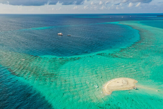 Aerial view of people on a small island with white sand, Thinadhoo, Vaavu Atoll, Maldives.