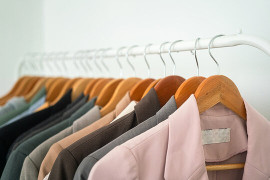 Row of colorful cotton coat suits are hanged by wooden cloth hanger on the rail. Fashion lifestyle object, close-up and selective focus.	
