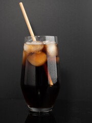 Glass of cola with ice on a black background. Close-up.