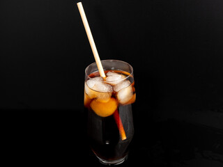 Glass of cola with ice on a black background. Close-up.