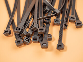 Fototapeta premium Black plastic cable ties on an orange background. Close-up.