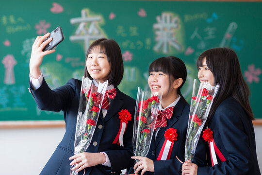 黒板の前で自分撮りをする女子学生