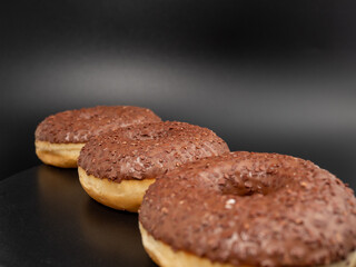 Chocolate donut with chocolate chips on a black background. close-up.