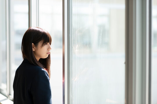 窓際で遠くを眺める女子学生
