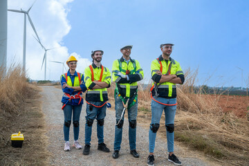 Team of male and female engineers perform maintenance on wind turbines, bringing wind energy to...