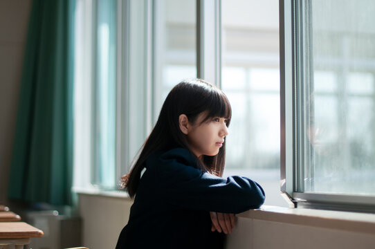 教室で外を眺める女子学生