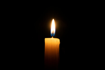 orange candle burns on a black background with a reflection copy space