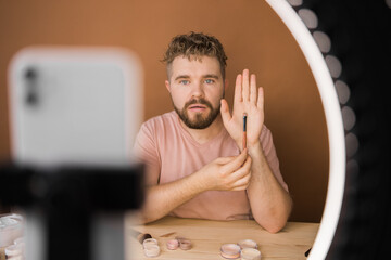 Male beauty blogger doing his make up and recording a video lesson his with mobile phone - vlog,...