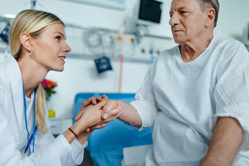 Young woman doctor holding hand, and talking with her patient.