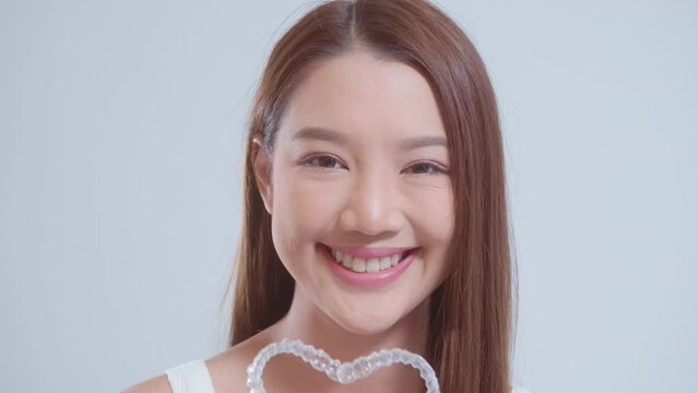 Young smiling woman holding invisalign braces over white background studio, dental healthcare and Orthodontic concept.
