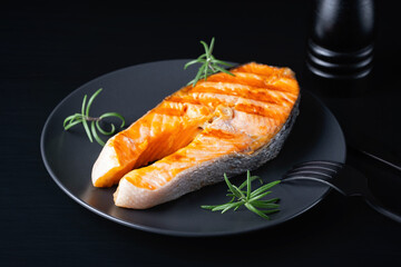 Fried salmon steak on black wooden table