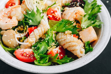 Seafood salad bowl. Green lettuce tomato salad with shrimps, scallop and squids