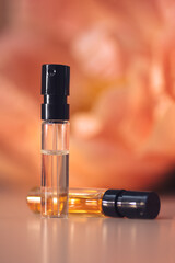 Two perfume samples with aroma water against peonies in soft focus. Face serum, essential oil, fruit peeling on floral background. Natural beauty product presentation. Front view. Mockup