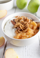 Grain free and gluten free breakfast bowl with greek yogurt, grated apples and nuts on white backgrounds