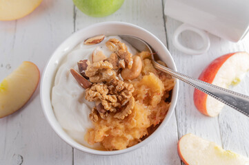 Grain free breakfast bowl with greek yogurt, grated apples, walnuts and brazil nuts on white background