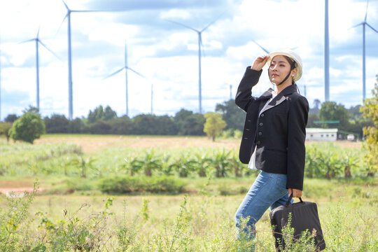 Young Asian businesswoman in suit with electric turbine as background
