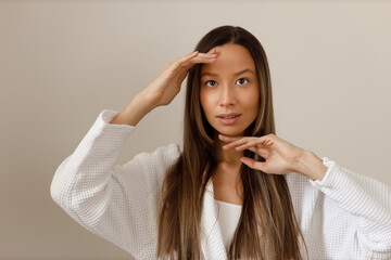 Young multiracial woman doing face building yoga and facial gymnastics self massage and rejuvenating exercises procedure.