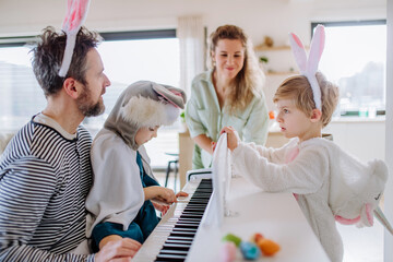 Happy family in easter costumes playing on the piano.