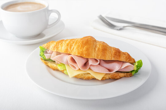 Croissant with ham and cheese on plate