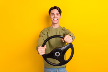 Portrait of satisfied young man hands hold wheel beaming smile isolated on yellow color background