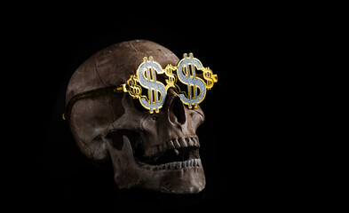 Model of a human skull in gold glasses with the symbol of the American dollar