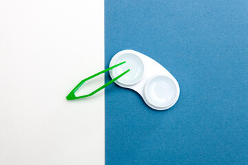 Contact lenses with a case and tweezers on a blue and white background