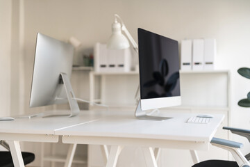 White table and chair with computer monitor and modern file cabinet in white home office