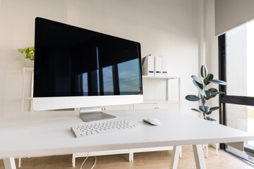 White table and chair with computer monitor and modern file cabinet in white home office