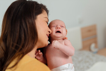 The little two-month girl cries at the mother on hands. Mother and daughter. children's cry and tears. Mom comforts a newborn baby