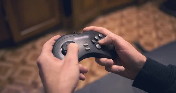 Fingers active, fast pressing game joystick buttons, close up. Man hands holding gaming console in room background. Entertainment activity. Gaming digital controller, gamepad. Gamer have fun, leisure