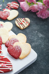 Valentines day cookies. Shortbread cookies inside sweet red heart with chocolate glaze on pink plate on grey background. Mothers day. Womans day. Sweet holidays baking. Valentines day card. Top view.