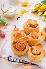 Obraz na płótnie Canvas Easter breakfast Holliday concept. Easter bunny buns rolls with cinnamon made from yeast dough with orange glaze, easter decorations, colored eggs on pink spring background. Easter Holliday card.