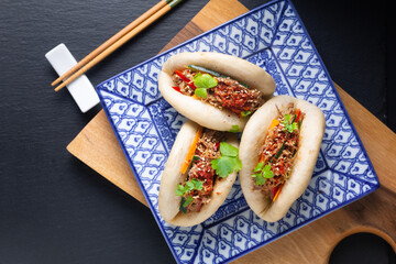Food concept Homemade organic Pulled Beef Bao Buns or Gua Bao in sqare plate on black background with copy space