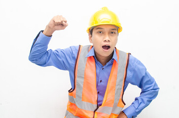 overjoyed asian male construction worker in blue shirt and orange vest with yellow safety helmet doing yes gesture by raising his fist.