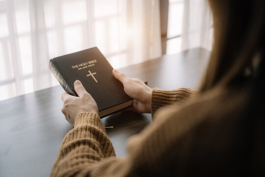 Close Up Of An Open Bible With A Cross For Morning Devotion On A Wooden Table With Window Lights.